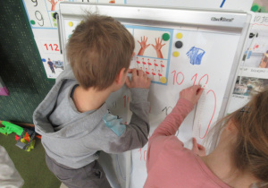 Dzieci mierzą elementy na tablicy.