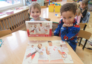 Chłopcy prezentują ułożone puzzle.