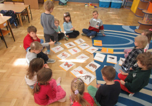 Dzieci siedzą w kole przed nimi obrazki.