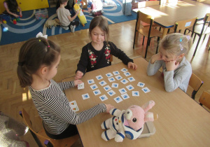 Dziewczynki siedzą przy stoliku i grają w memory.