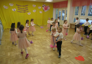 Dzieci maszerują z "miotełkami" tworząc dwa koła.