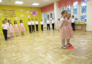 Dwie dziewczynki recytują wiersze dla Babci i Dziadka, pozostałe dzieci stoją w półkolu.