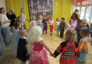 Dzieci tańczą w kole podczas balu karnawałowego.