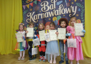Dzieci pozują do zdjęcia z dyplomami i nagrodamiza udział w konkursie.