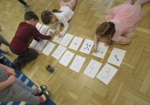 Dzieci kolorują leżąc na podłodze.