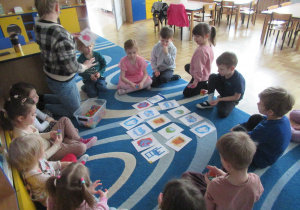 Dzieci siedzą w kole podczas zajęć z języka angielskiego.