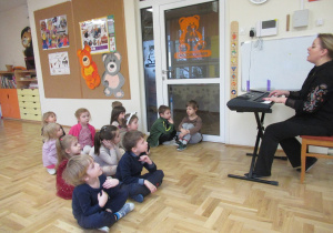 Dzieci siedzą na podłodze podczas rytmiki.