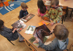 Dzieci oglądają obrazki dinozaurów w okularach 3D.