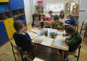 Dzieci pracują przy stolikach.