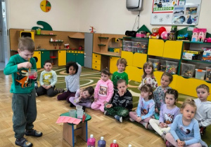 Chłopiec miesza farbę w plastikowym kubku