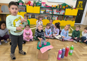 Chłopiec miesza farbę w plastikowym kubku