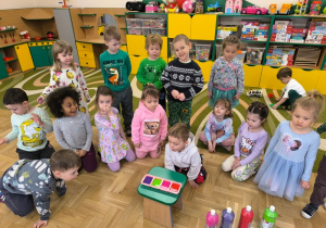 Dzieci patrzą na foremki wypełnione kolorowymi płynami