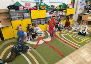 Chłopiec przechodzi po konturze numeru 112 ułożonego z szarf