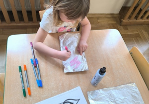 Dziewczynka rysuje pisakiem po folii aluminiowej