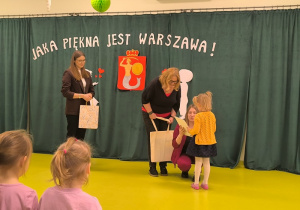 Dziewczynka odbiera dyplom i nagrodę za udział w konkursie plastycznym