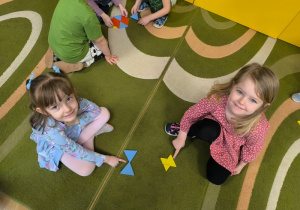 Dziewczynki pokazują swoje wzory ułożone z klocków w kształcie trójkąta