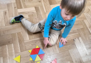 Chłopiec wskazuje wzór ułożony z klocków w kształcie trójkąta