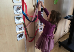 Dziewczynka przyczepia wstążkę do obrazka