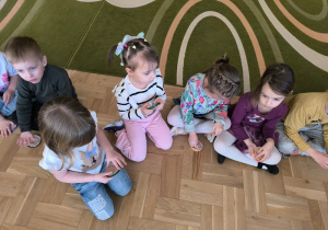 Dziewczynka odciska w masie solnej sylwetę dinozaura