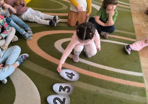 Dziewczynka układa papierowe jajka oznakowane cyframi