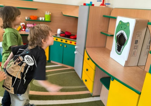 Chłopiec wrzuca piłkę do pudełka oznakowanego paszczą dinozaura