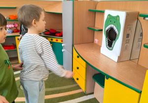Chłopiec wrzuca piłkę do pudełka oznakowanego paszczą dinozaura