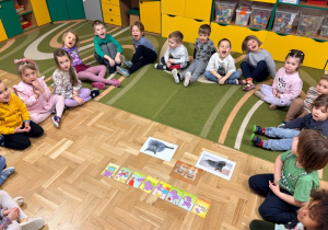 Dzieci siedzą wokół obrazków przedstawiających koty