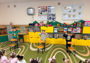 Dzieci stoją za krzesłami