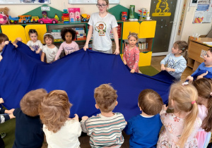 Dzieci trzymają niebieski materiał