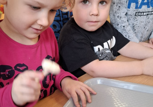 Dzieci próbujące rozbić jajko i odszukać schowane w nim skarby