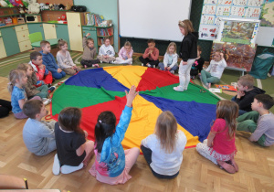 Dzieci siedzą wokół chusty animacyjnej.