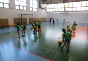 Dzieci pokonują tor przeszkód z piłkami.