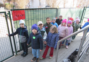 Dzieci stoją ustawione w pary przy tabliczce z napisem start.