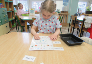 Dziewczynka siedzi przy stole i układa wyrazy.