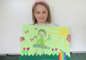 Dziewczynka prezentuje pracę plastyczną wykonaną na konkurs "Pani Wiosna".