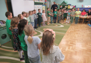 Dzieci stoja w półkolu podczas warsztatów wiosennych z rodzicami.