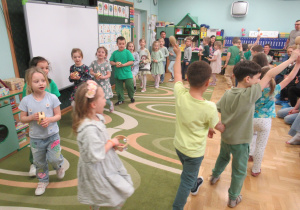 Dzieci maszerują w kole grając na instrumentach.