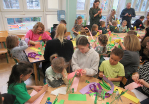 Dzieci z rodzicami wykonują kwiaty z papieru.