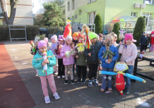 Dzieci stoją w ogródku przedszkolnym z Marzannami.