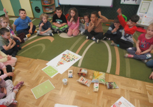 Dzieci siedzą w kole podczas zajęć o produktach ekologicznych.