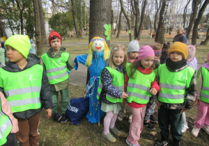 Dzieci stoją wokół Marzanny opartej o drzewo.