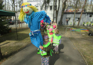 Dzieci maszerują, dziewczynka trzyma Marzannę.