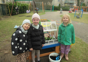 Dziewczynki pozują do zdjęcia w ogródku przedszkolnym.